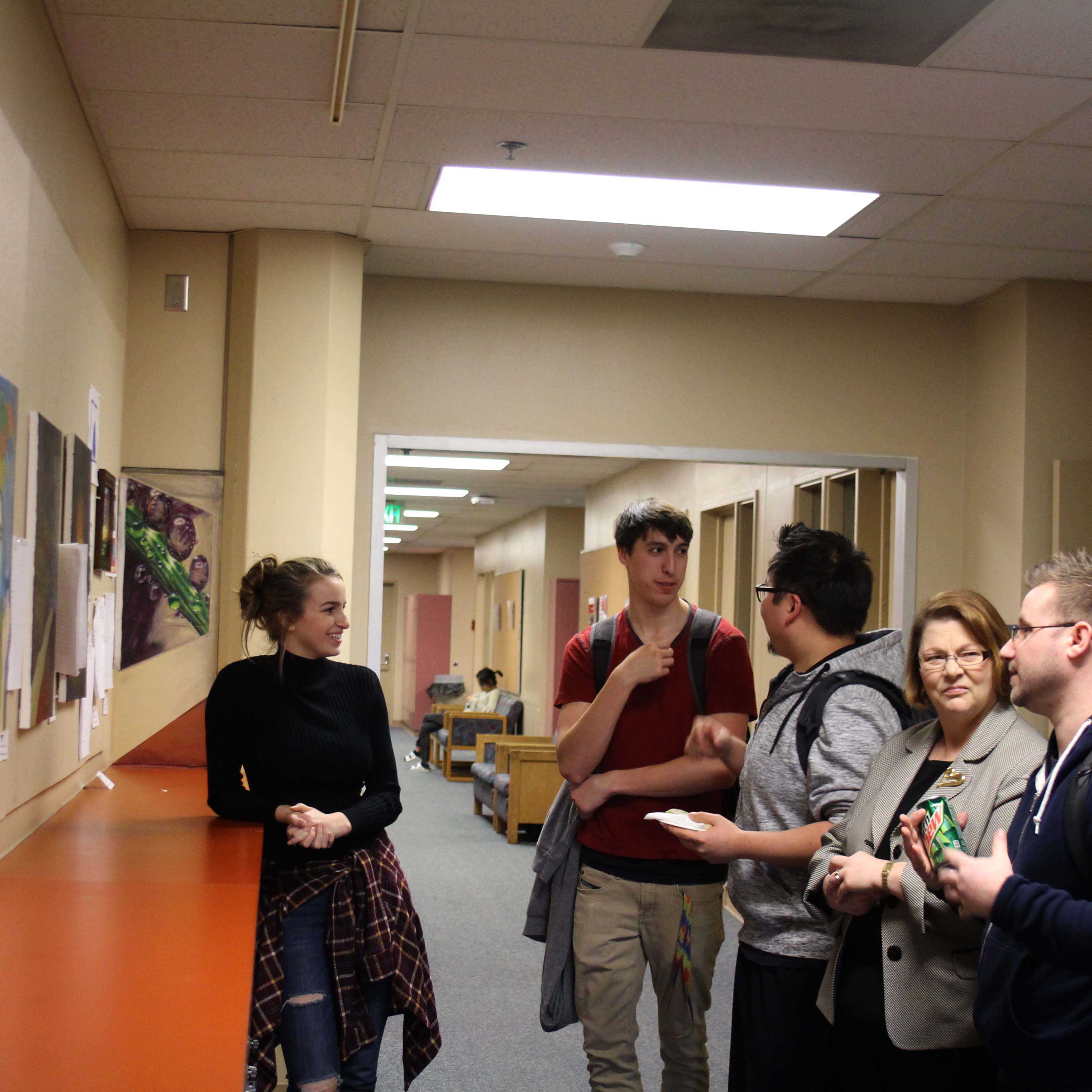 The painter Jessica Van Alstine, the poet Nathaniel Devish discuss the art as Denise Yochum listens to the poet Anthony Mucciacciaro explain his work.