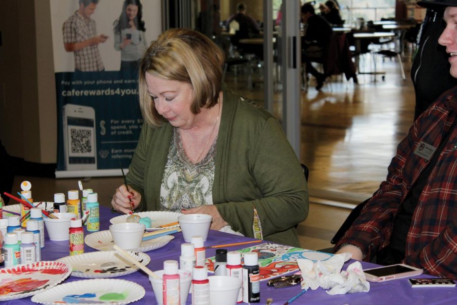 Allie Morrow and Will Syhlman paint at a table with other students.
