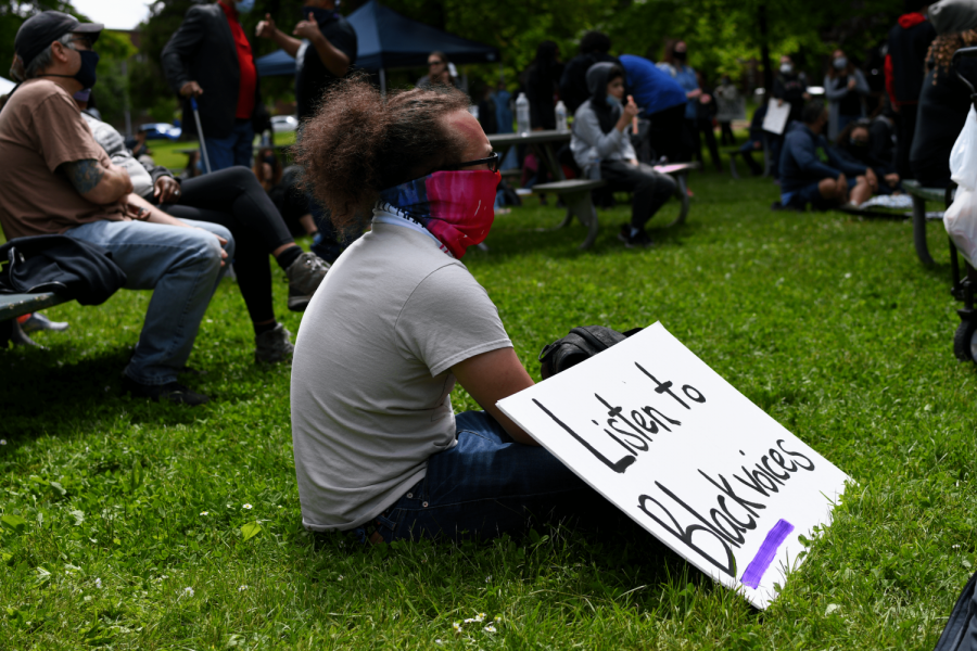 A man listens intently to the speakers with his sign.